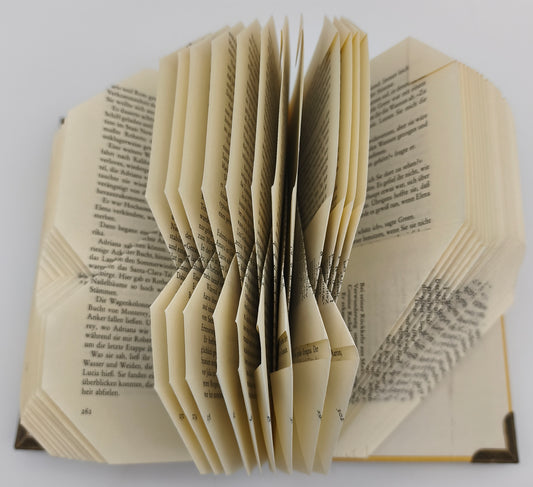Aufgeschlagenes gefaltetes Buch mit gebrochenem Herz, Detailansicht der gefalteten Seiten von oben