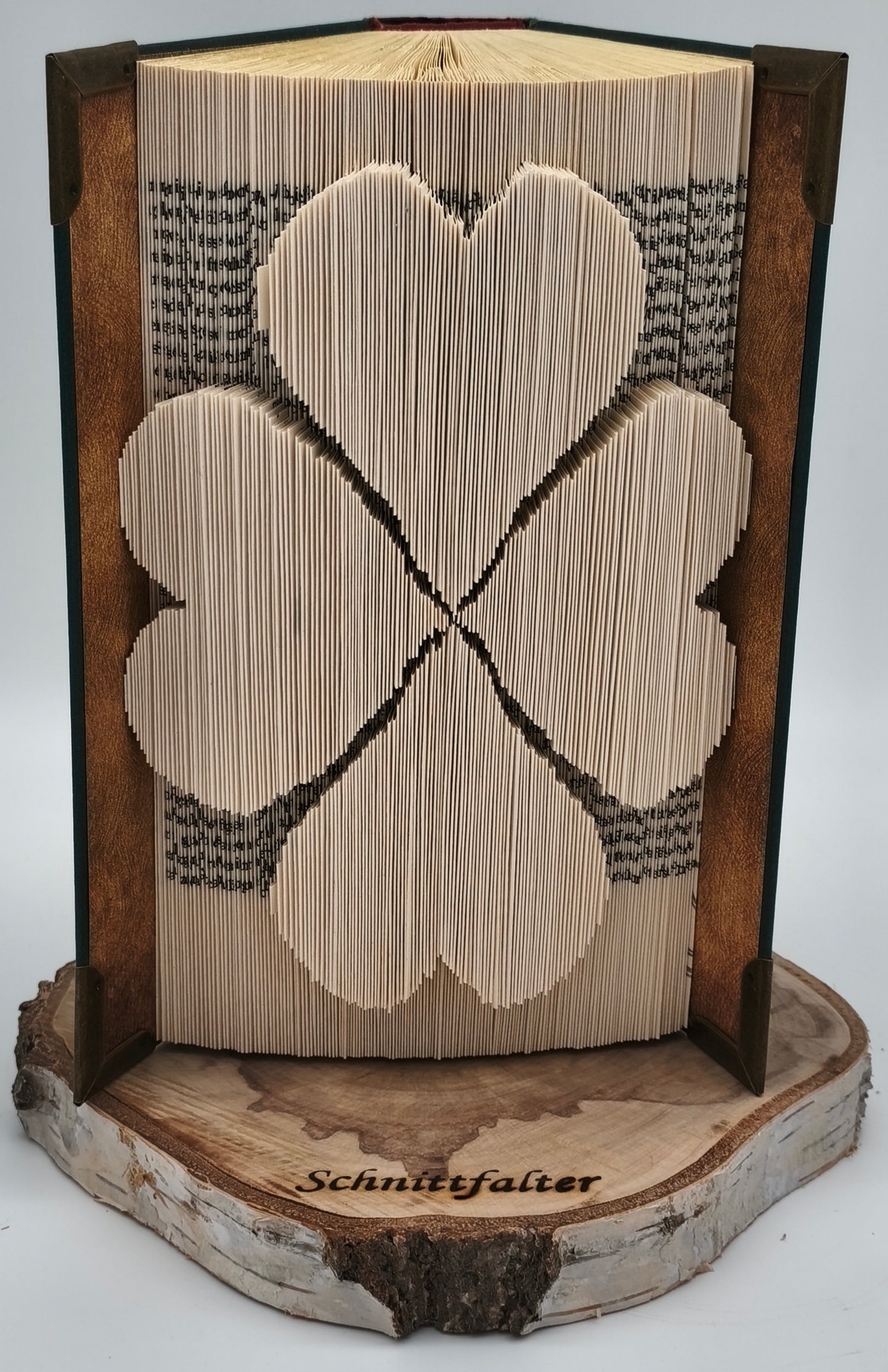 Gefaltetes Buch mit Kleeblatt-Motiv aus Buchfaltkunst auf Birkenscheibe, Frontansicht