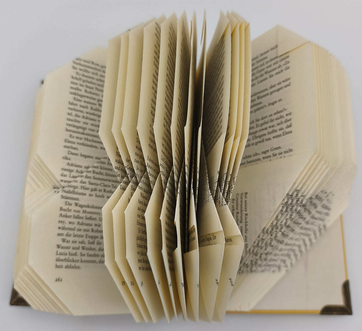 Aufgeschlagenes gefaltetes Buch mit gebrochenem Herz, Detailansicht der gefalteten Seiten von oben