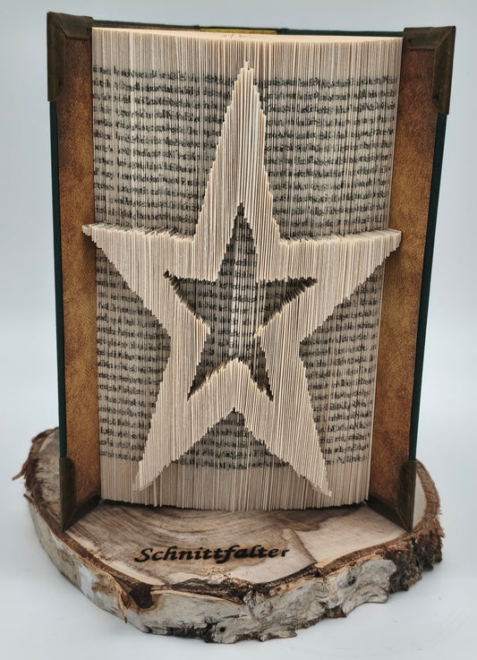 Buchfaltkunst Stern, handgefaltet aus altem Buch auf natürlicher Baumscheibe mit eingebranntem Schnittfalter-Logo, Frontansicht