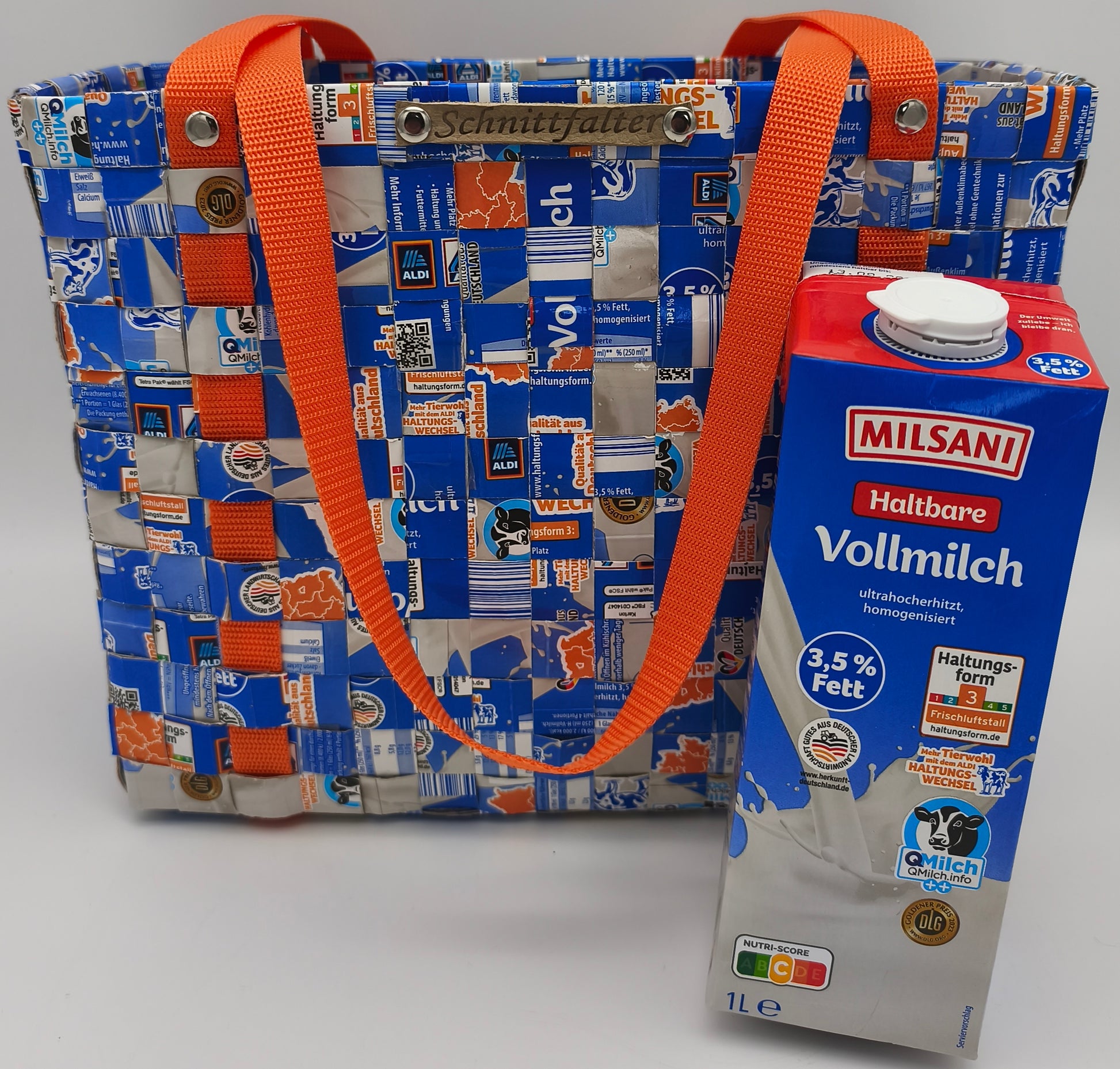 Upcycling Einkaufstasche Blau-Orange aus Milch-Tetrapack mit orangem Gurtband, Größenvergleich zur 1-Liter-Vollmilch-Packung, Schnittfalter-Label sichtbar