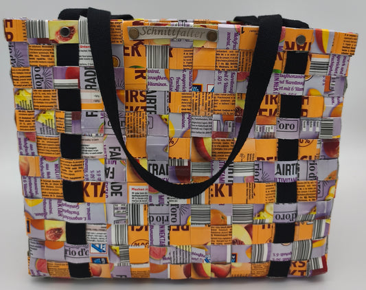 Upcycling-Einkaufstasche aus Orangensaft-Tetrapacks, geflochten, mit schwarzem Gurtband und Schnittfalter-Label, Frontansicht