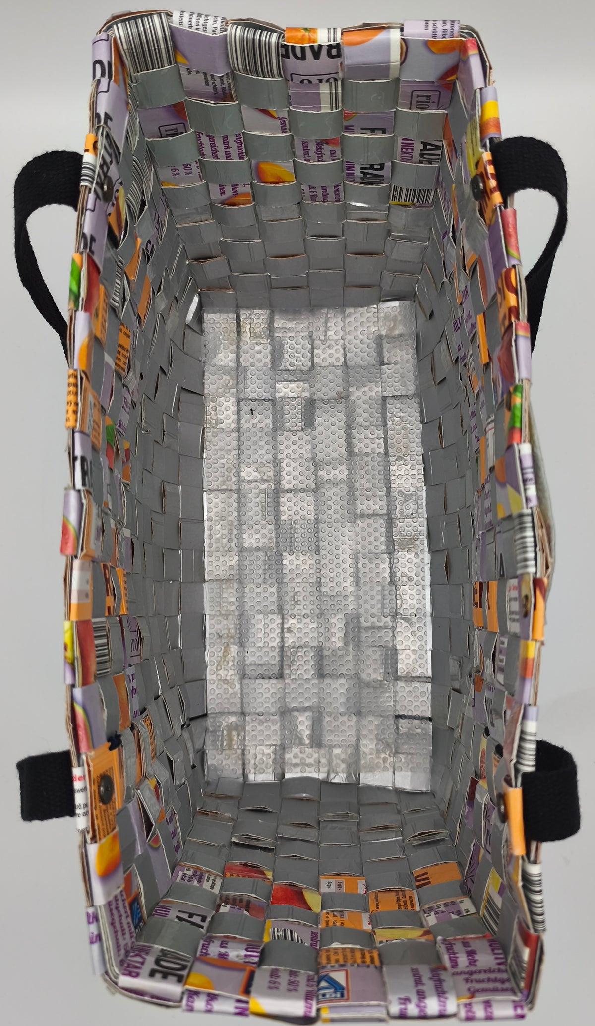  Innenansicht der Upcycling-Tetrapack-Tasche mit silberner Aluminium-Innenseite und strukturiertem Boden, schwarze Gurtbandstege seitlich sichtbar