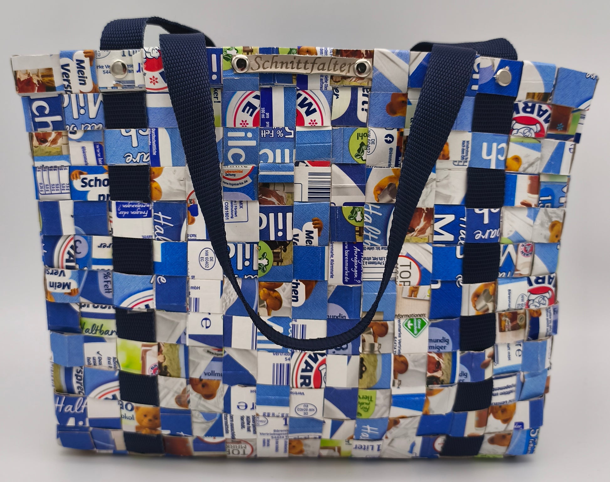 Upcycling Einkaufstasche aus Milch Tetrapacks in Blau-Weiß, geflochten mit dunkelblauem Gurtband, Schnittfalter Label und Schrauben sichtbar, Frontansicht